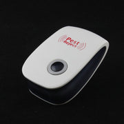 A white and black pest repeller with a black button is shown on a dark, reflective surface.