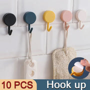 Self-adhesive utility hooks holding kitchen utensils and towels.