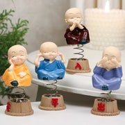 Baby monk figurines displayed on a car dashboard