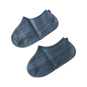 A pair of dark gray silicone shoe covers with textured soles is displayed against a plain white background.